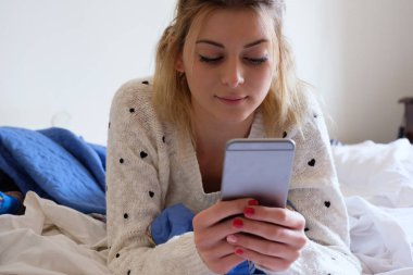 Yatakta yatıyordu telefon kullanan kız