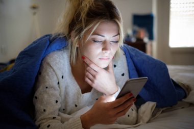 Yatağa atma sırasında cep telefonu tutan hayal kırıklığına üzgün kadın