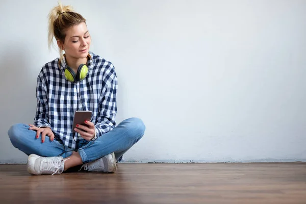 Chica sentada en el suelo y utilizando el teléfono inteligente — Foto de Stock