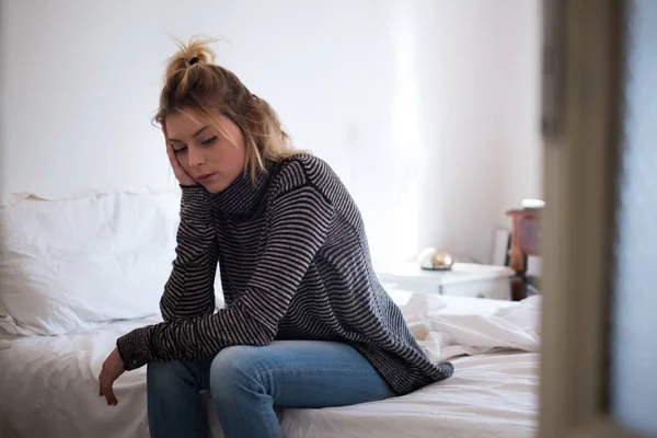 Sad young tired woman sitting on the bed — Stock Photo, Image