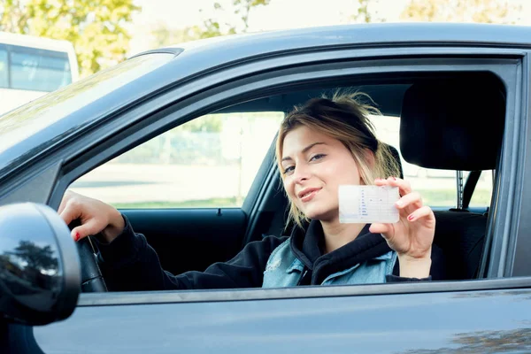 Девушка портрет sititng в своей машине и водительские права — стоковое фото