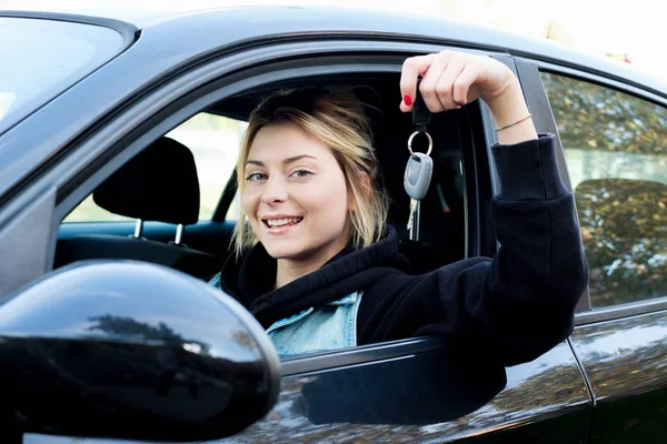 Jeune fille heureuse tenant la clé de voiture assise dans sa nouvelle voiture — Photo