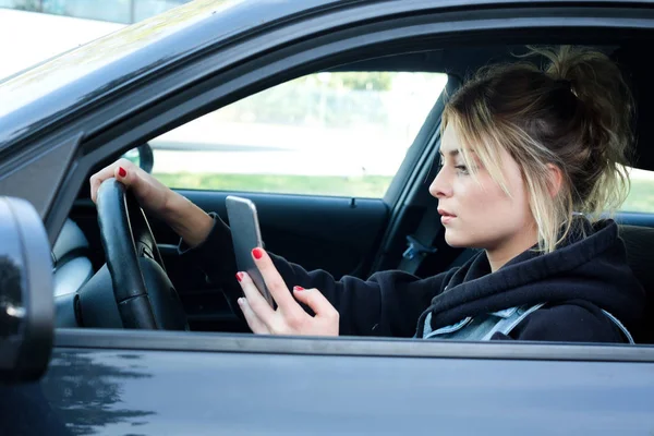 Kvinde kørsel bil distraheret af hendes mobiltelefon - Stock-foto