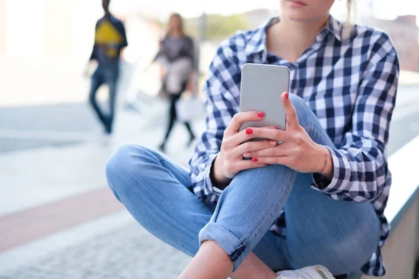 Meisje houdt van mobiele telefoon op straat achtergrond van de stad — Stockfoto