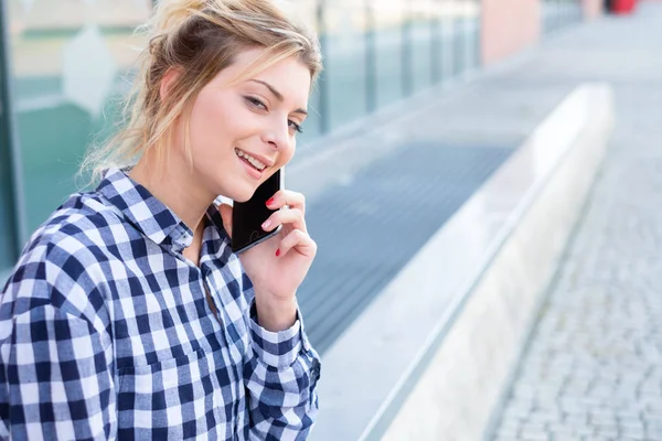 Menina segurando telefone celular no fundo da rua da cidade — Fotografia de Stock