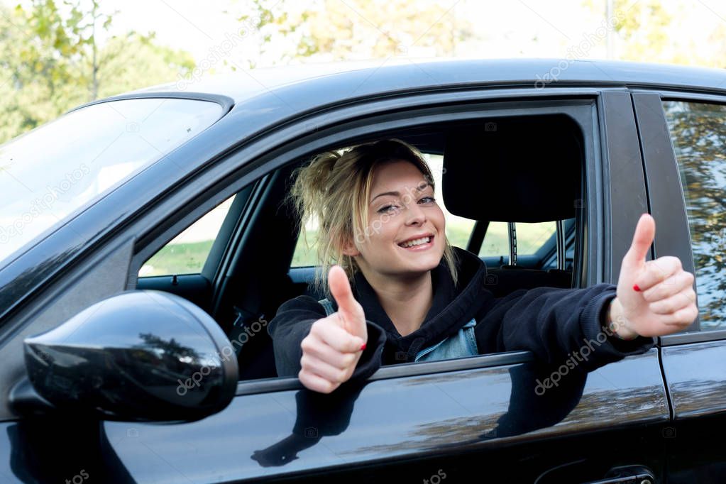 Happy girl with thumb up driving her new car