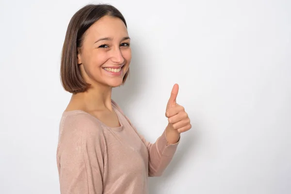 Chica sonriendo con el pulgar hacia arriba gesto en el fondo —  Fotos de Stock