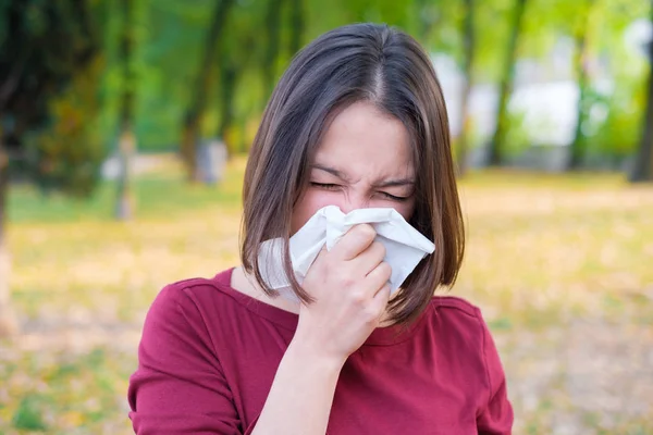 Mulher espirrando em um kleenex por causa do frio e da gripe — Fotografia de Stock