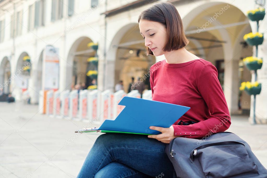 Female student with books and school bag in the city