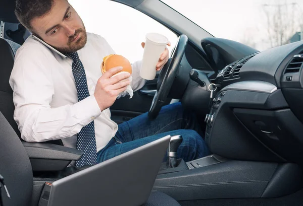 Hombre comiendo comida de engorde y trabajando sentado en coche — Foto de Stock