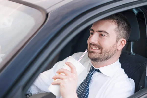 Мужчина пьет и водит машину, сидя в машине — стоковое фото