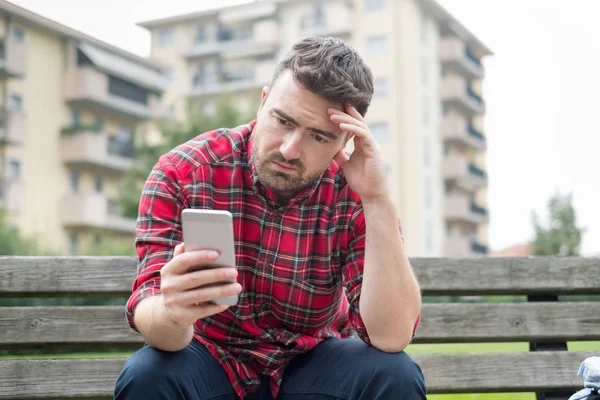 Triste e sem emprego homem sentado em um banco de parque — Fotografia de Stock