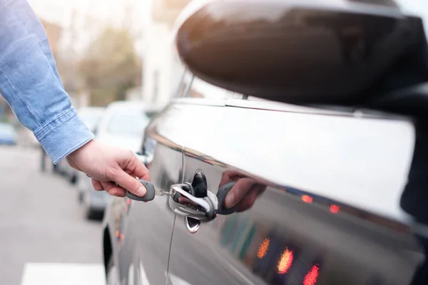 Mano sosteniendo una llave del coche y abriendo la puerta del coche — Foto de Stock