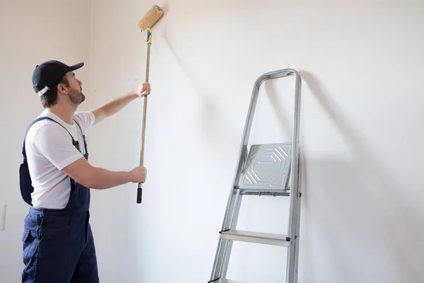 Trabalhador pintor profissional está pintando uma parede — Fotografia de Stock