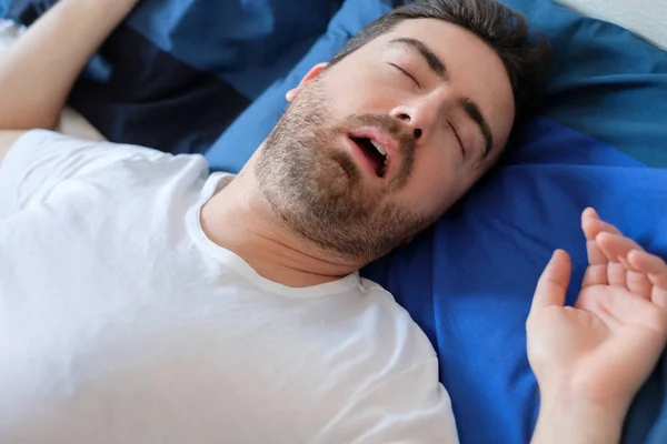Человек в постели страдает от синдрома апноэ во сне — стоковое фото