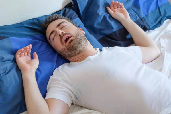 Hombre en cama que sufre de síndrome de apnea del sueño — Foto de Stock