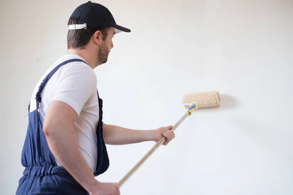 Trabalhador pintor profissional está pintando uma parede — Fotografia de Stock