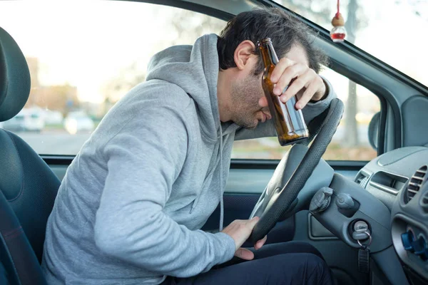 Borracho y conduciendo un coche con una botella de alcohol — Foto de Stock