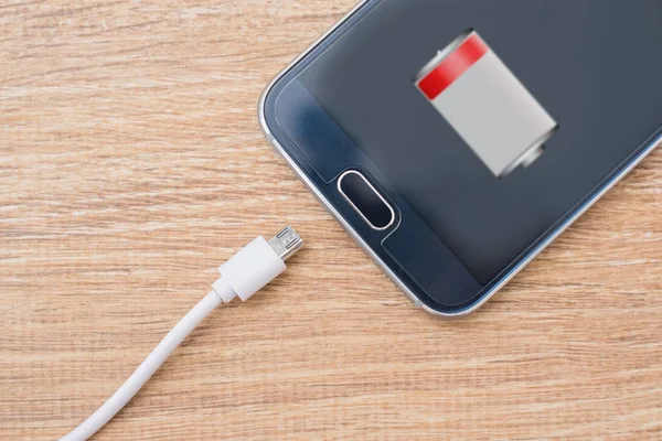 Mobiltelefon och batteri laddare kabel på skrivbord — Stockfoto