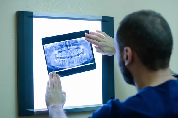 Confident male dentist examining teeth on x ray chart