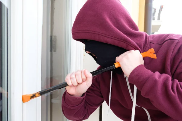 Hooded burglar forcing window shutter lock — Stock Photo, Image