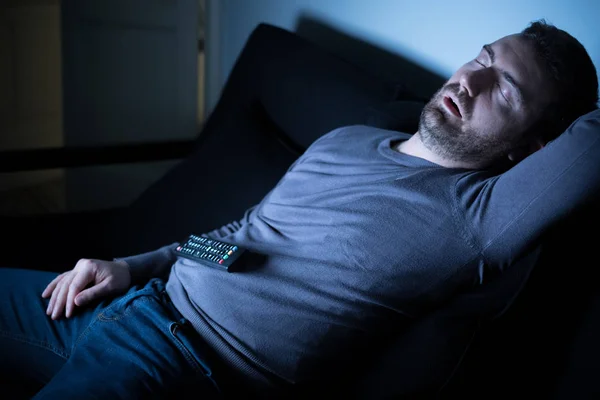 Znuděný člověk spí a sledování televize v noci — Stock fotografie