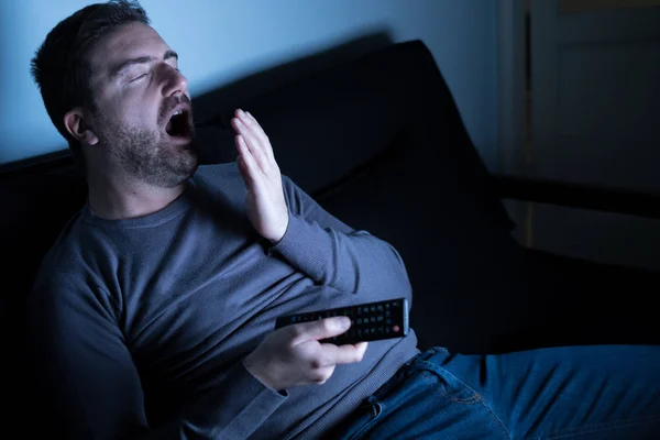 Znuděný člověk dívat se na televizi v noci — Stock fotografie
