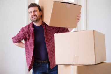 Man feeling back ache cramp moving heavy boxes clipart
