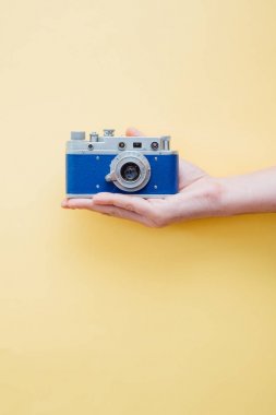 Vintage tarzı kamera sarı arka plan üzerinde tutan el