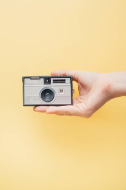 Vintage tarzı kamera sarı arka plan üzerinde tutan el