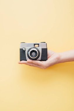 Vintage tarzı kamera sarı arka plan üzerinde tutan el