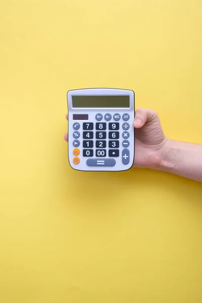 Calculadora mão segurando no fundo amarelo — Fotografia de Stock
