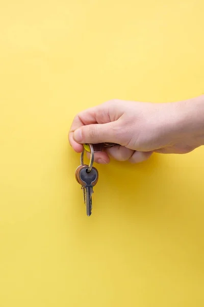 Рука держит ключи изолированы на желтом фоне — стоковое фото