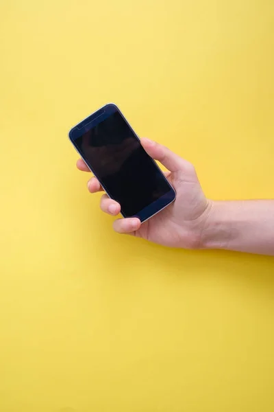 Mão segurando smartphone isolado no fundo amarelo — Fotografia de Stock