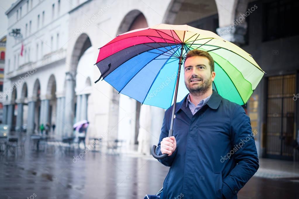 Rainy day in the city and businessman holding umbrella