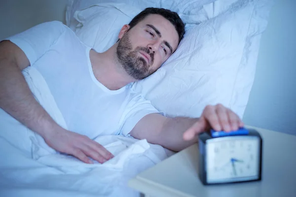 Расстроенный мужчина пытается спать в своей постели ночью — стоковое фото