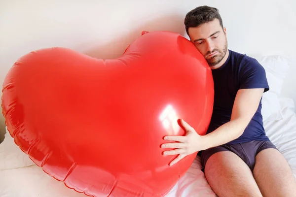 Sad man need love and hugs a big red heart shaped balloon
