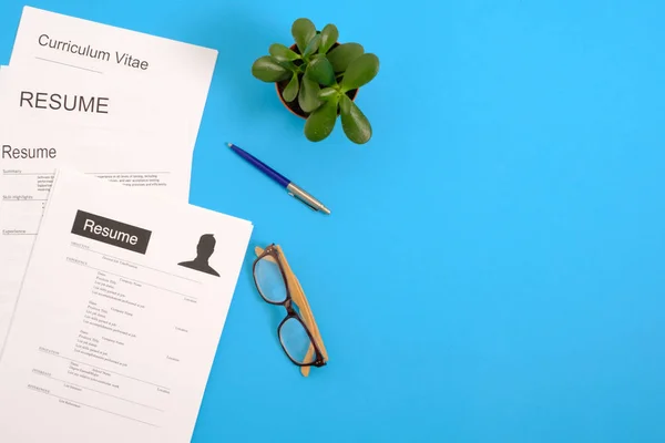 Visão de alto ângulo do curriculum vitae na área de trabalho azul — Fotografia de Stock