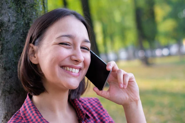 Jovem segurando telefone inteligente e falando — Fotografia de Stock