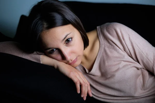 Сумна дівчина на дивані портрет обличчя вночі — стокове фото