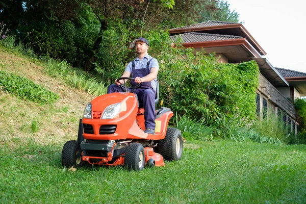 Tuinman rijden een paardrijden grasmaaier in tuin — Stockfoto