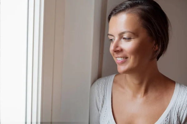 Mujer pacífica mirando por la ventana —  Fotos de Stock