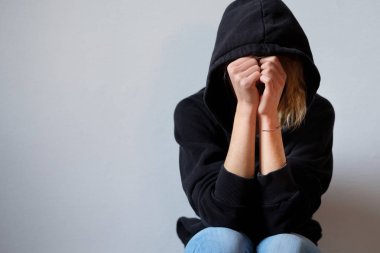 Genç kız yüzünü kapüşonlu sweatshirt b izole altında gizleme