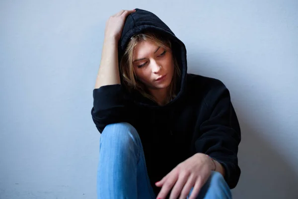 Young girl hiding her face under hooded sweatshirt isolated on b — Stock Photo, Image