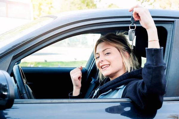 Fille assise dans sa voiture et montrant la clé — Photo