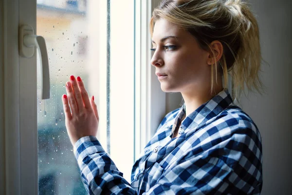 Chica joven mirando por la ventana y sintiéndose triste — Foto de Stock