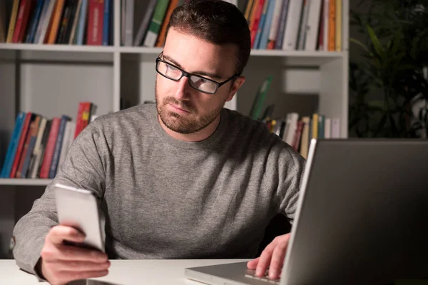 Giovane uomo che utilizza computer portatile e smartphone — Foto Stock