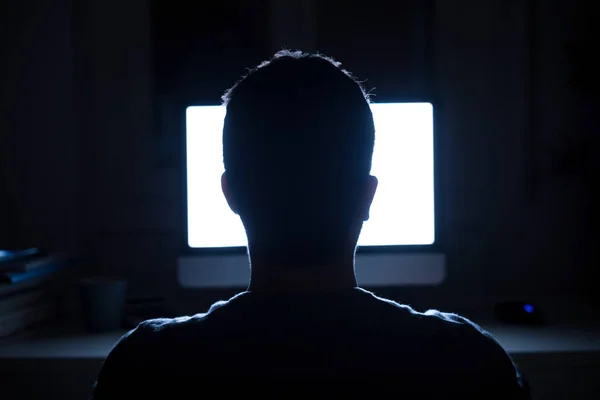 Hombre sentado frente al monitor de la computadora por la noche — Foto de Stock