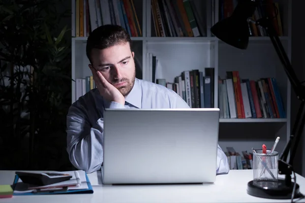 Businessman working and watching laptop display at night