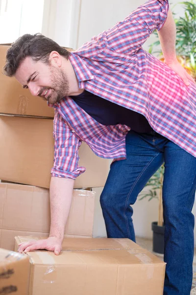 Man moving boxes and feeling back pain because heavy weight — Stock Photo, Image